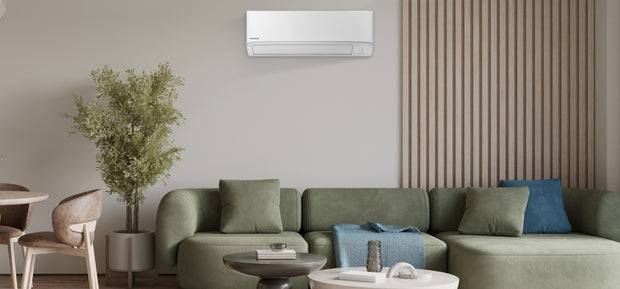 Modern living room with a green couch below a white wall-mounted air conditioner unit