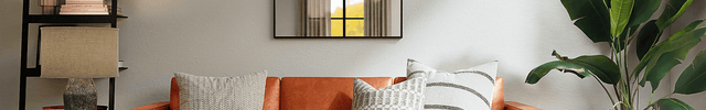 A small living room with an orange couch situated below a TECO wall-mounted air conditioner unit