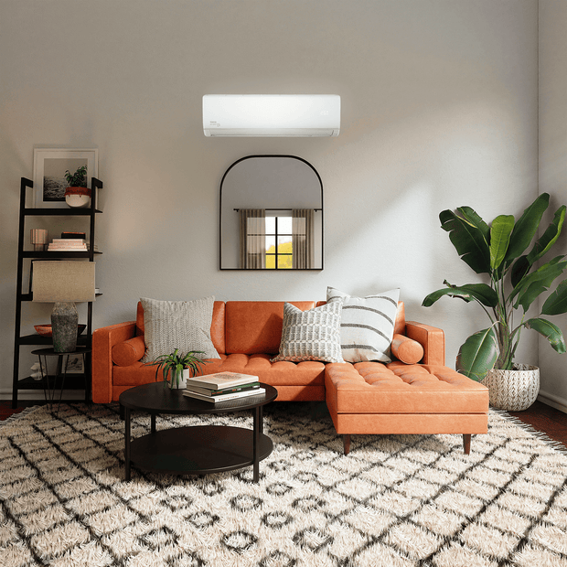 A small living room with an orange couch situated below a TECO wall-mounted air conditioner unit